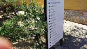 Señal con indicaciones a diferentes servicios, como parque infantil, recepción, productos toscanos, estacionamiento y otros.