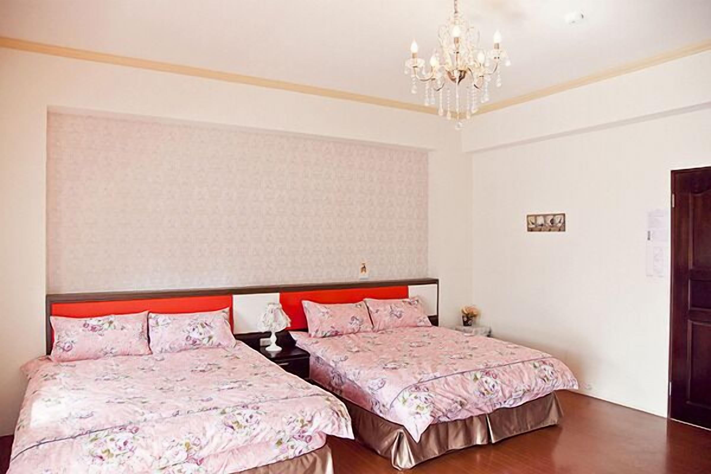 Una habitación de hotel con dos camas, una araña y una pared grande con un diseño discreto.