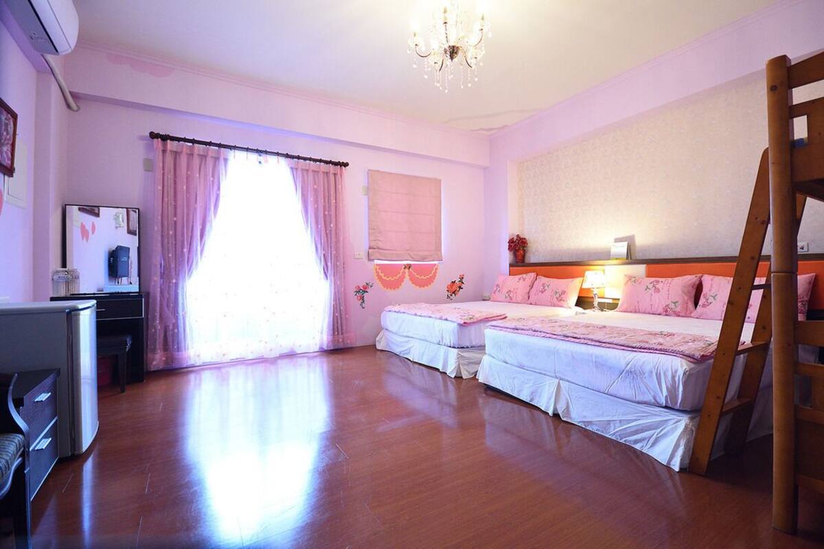 A bedroom with two beds, a desk, and a chair.