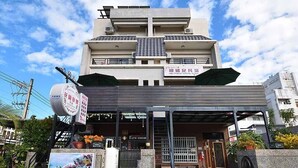 A multi-story building with a covered entrance, potted plants, and a signboard. - The Garden Rose B&B (Taitung)