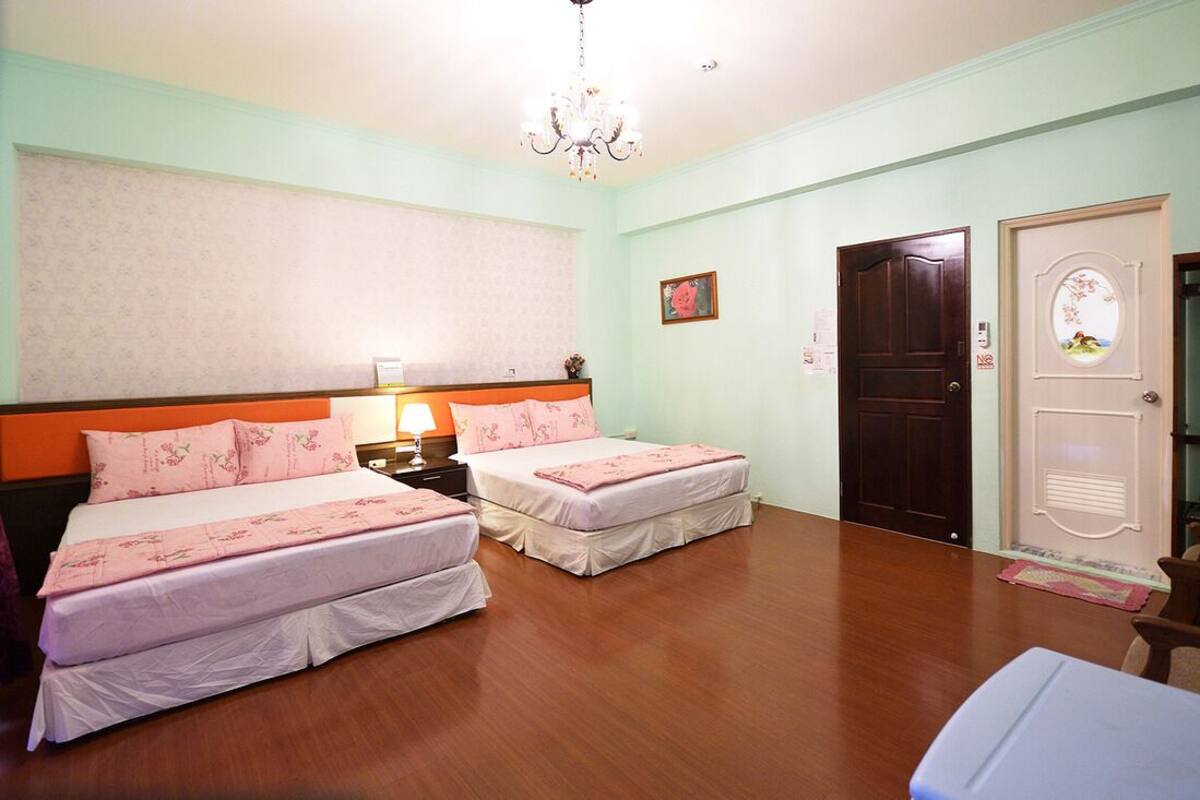 A room with two beds, a chandelier, and a door with a window.