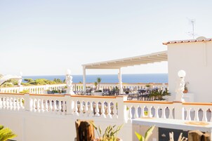 Una terraza con mobiliario exterior, barandilla blanca y vista al mar.