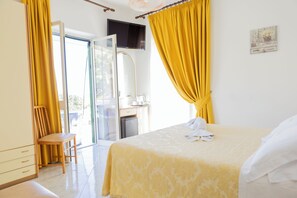 Une chambre d’hôtel avec un lit, une chaise, un bureau et un téléviseur.