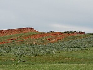 A vast, open landscape with rolling hills and a flat grassy area.