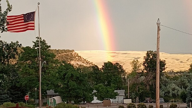 A park with a flag, a rainbow, and a mountainous backdrop. - El Rancho Motel (Thermopolis)
