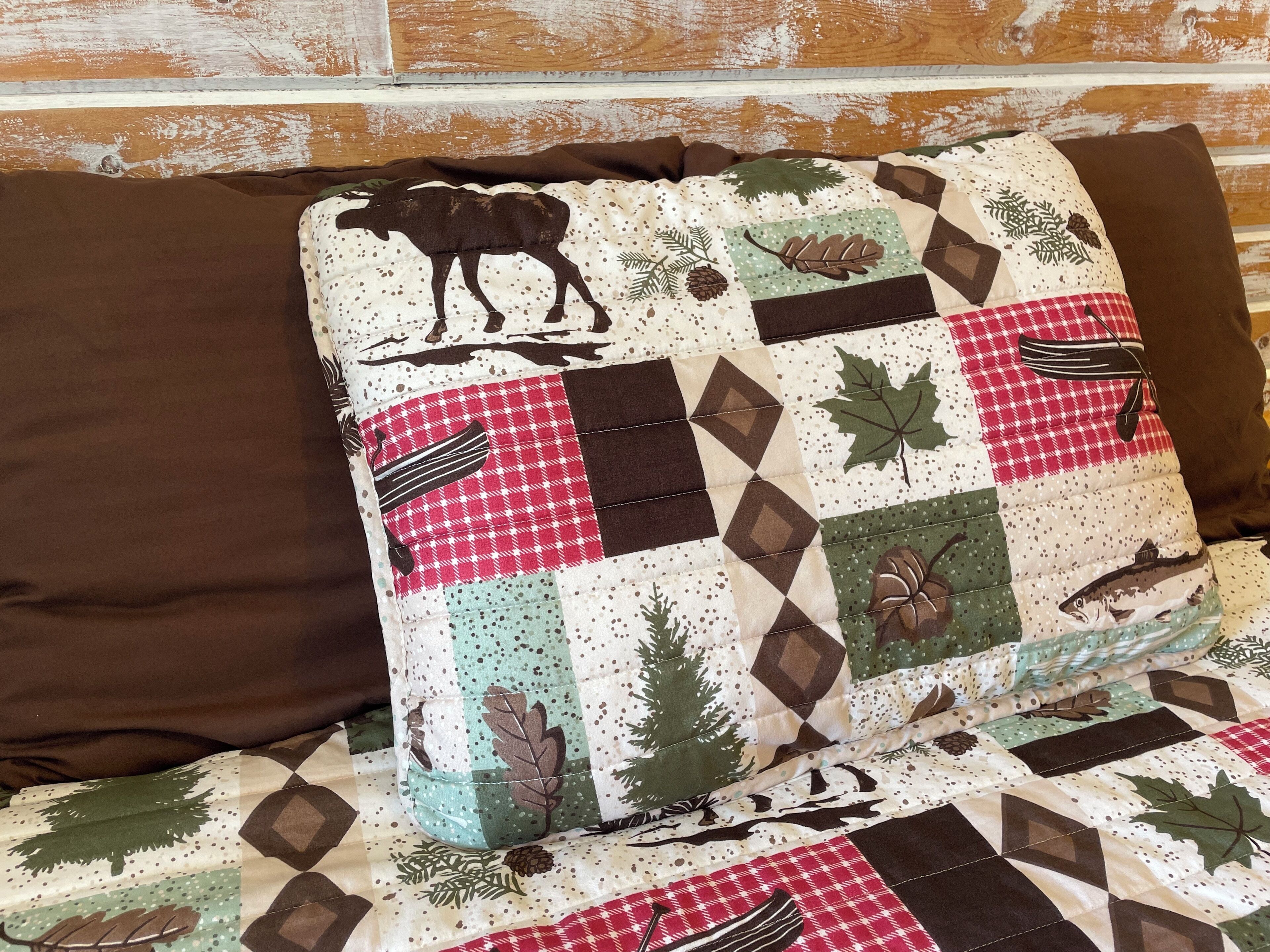 Un coussin matelassé orné d’un motif d’élan, accroché à un mur en bois.