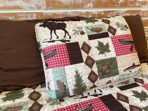 A quilted pillow with a moose design on a wooden wall.