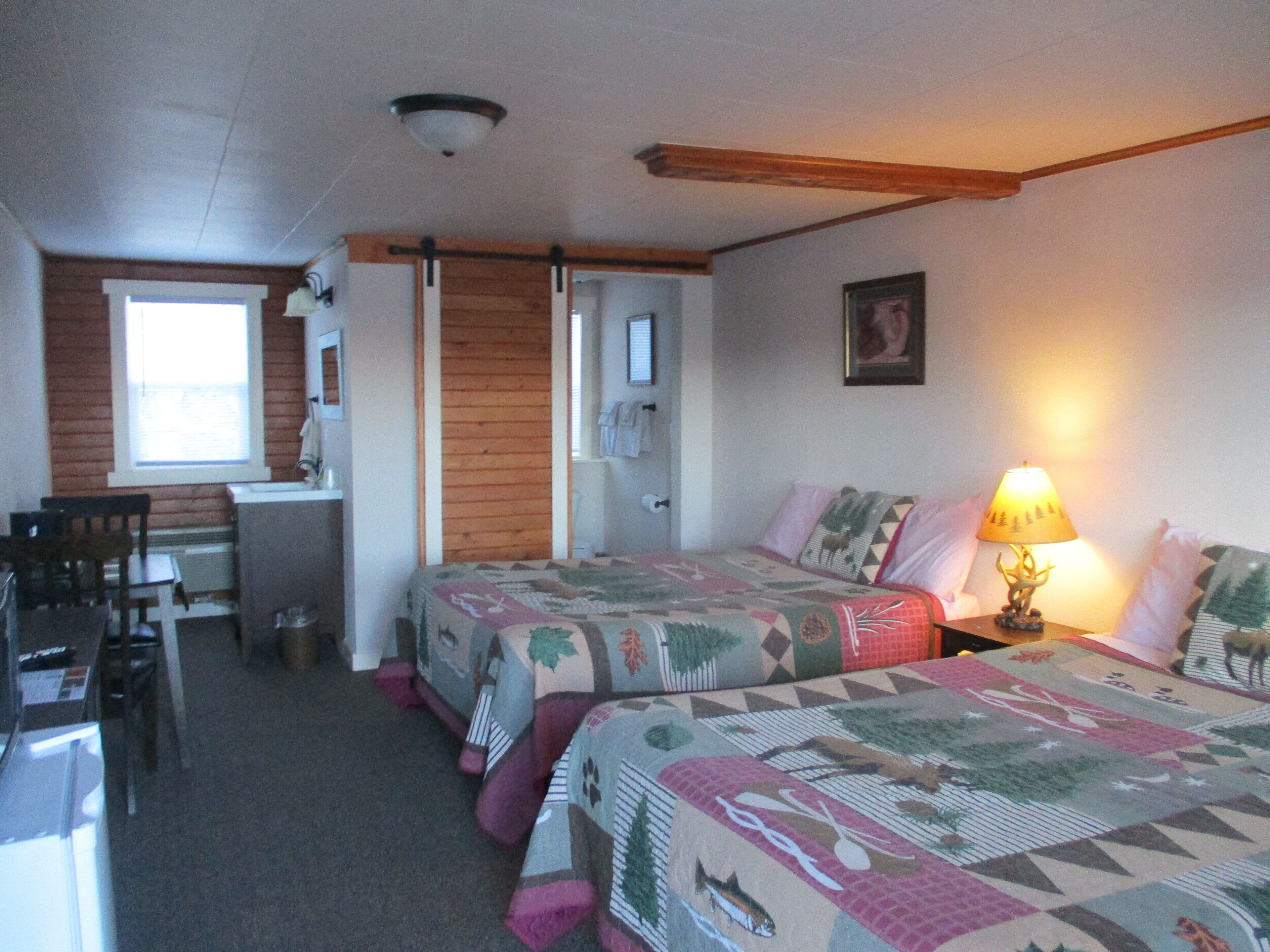 A bedroom with two beds, a desk, and a chair.
