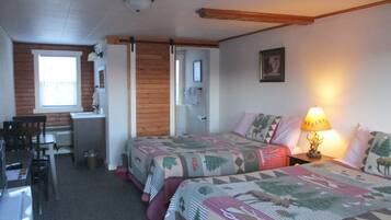 A bedroom with two beds, a desk, and a chair.