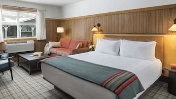A hotel room with a bed, a sofa, a desk, and a window.