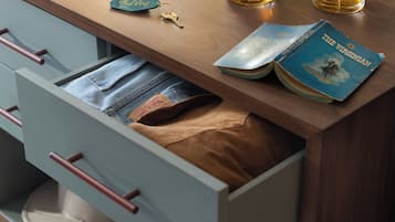 Una mesa de madera con un libro, un vaso de whisky, un llavero y un cajón con un objeto marrón en su interior.
