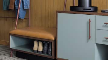 Une pièce avec un mur en bois, un téléviseur fixé au mur, un banc doté d’un espace de rangement en dessous et un porte-chaussures.