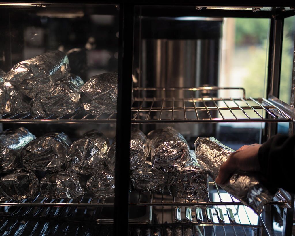 An oven with food items wrapped in aluminum foil.