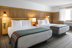 A hotel room with two beds, wooden panel walls, and a window with curtains. - The Virginian Lodge, an Outbound Hotel (Jackson)