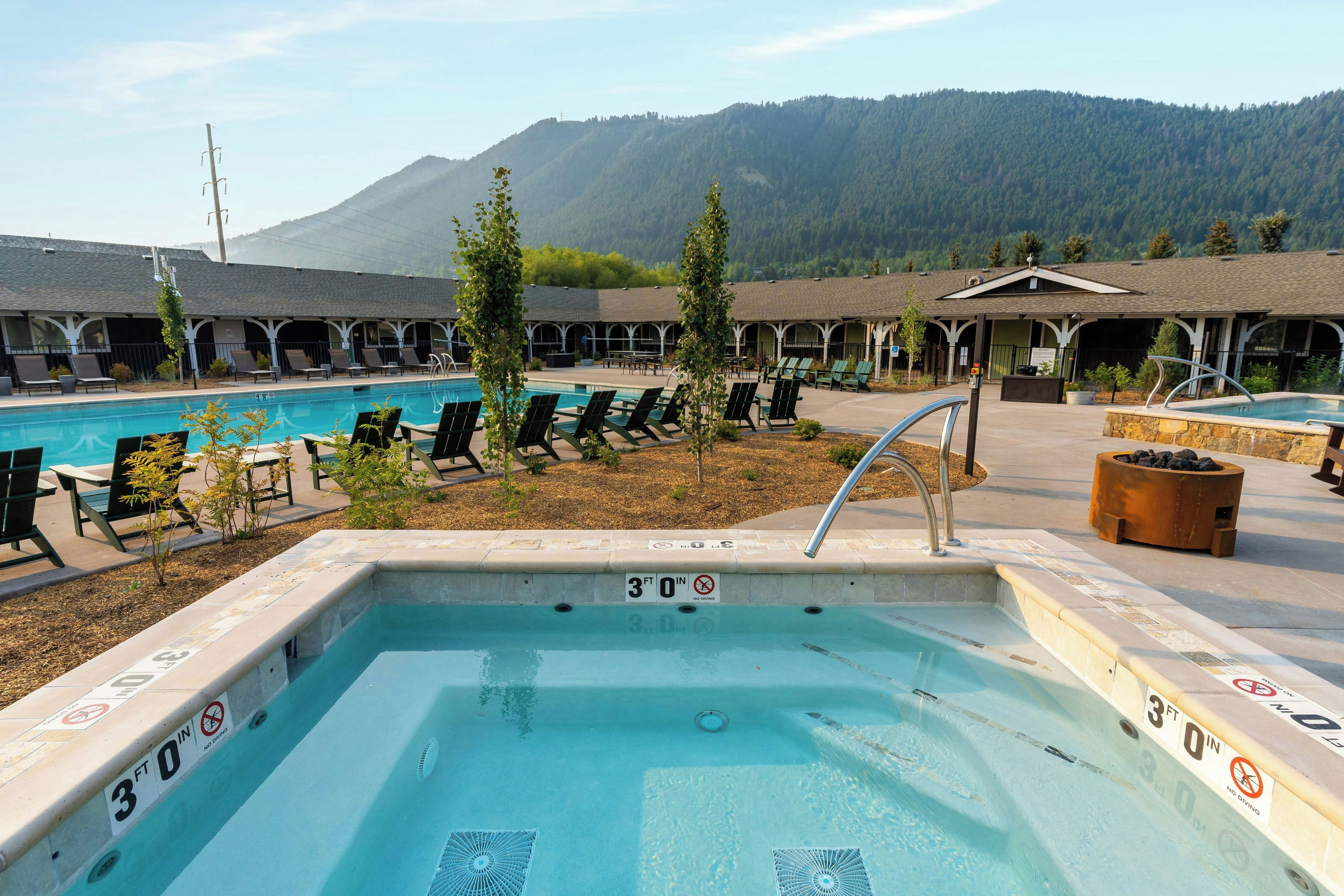 A pool area with a 30 ft depth, lounge chairs, and a mountain backdrop.