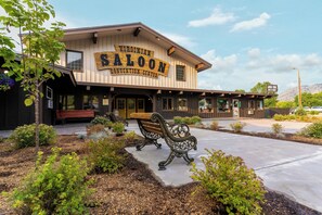 A building with a sign reading 'VIRGINIAN SALOON CONVENTION CENTER' with outdoor seating and landscaping. - The Virginian Lodge, an Outbound Hotel (Jackson)