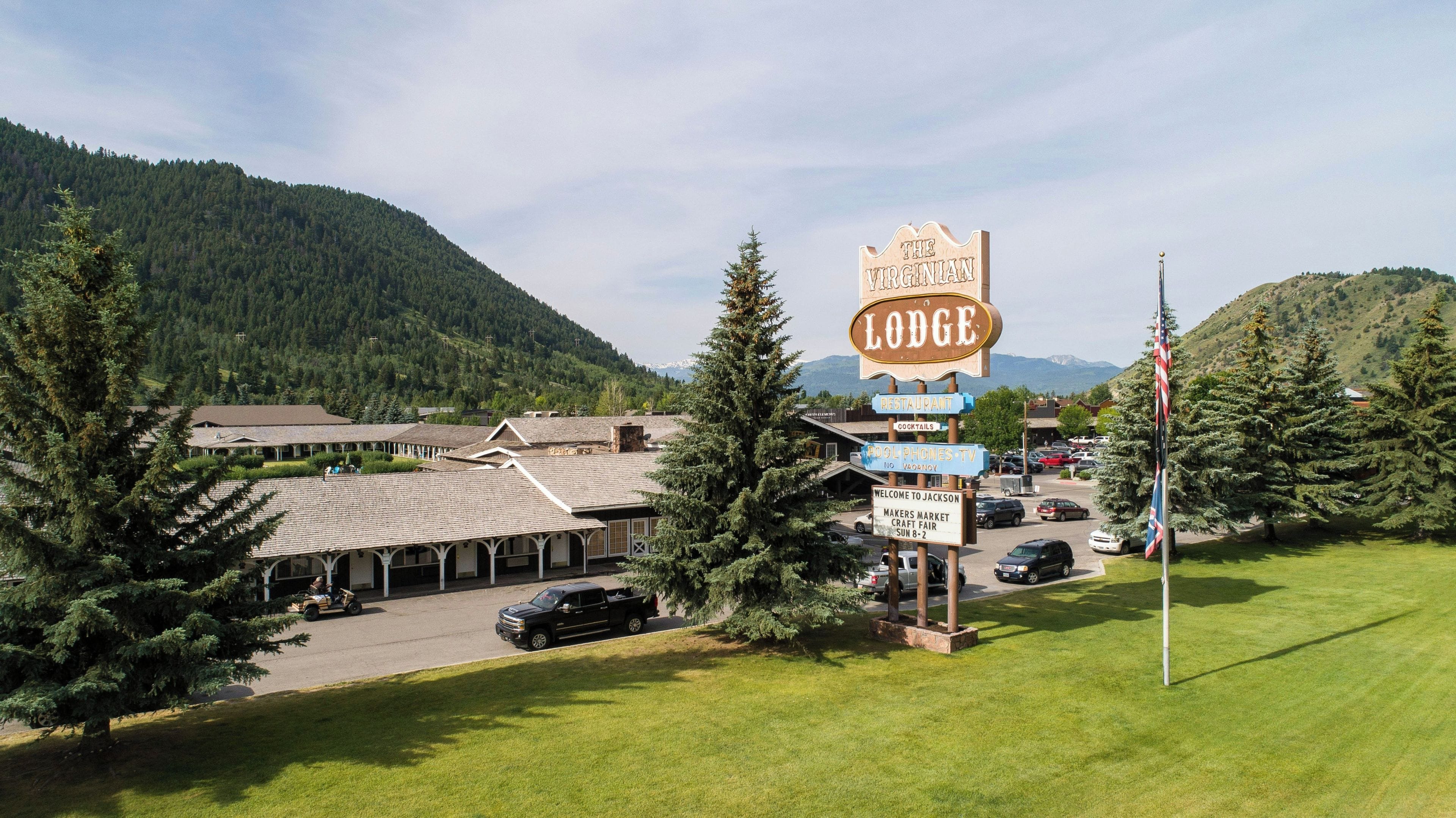 A lodge with a signboard indicating amenities like a restaurant, cocktails, and a market fair.