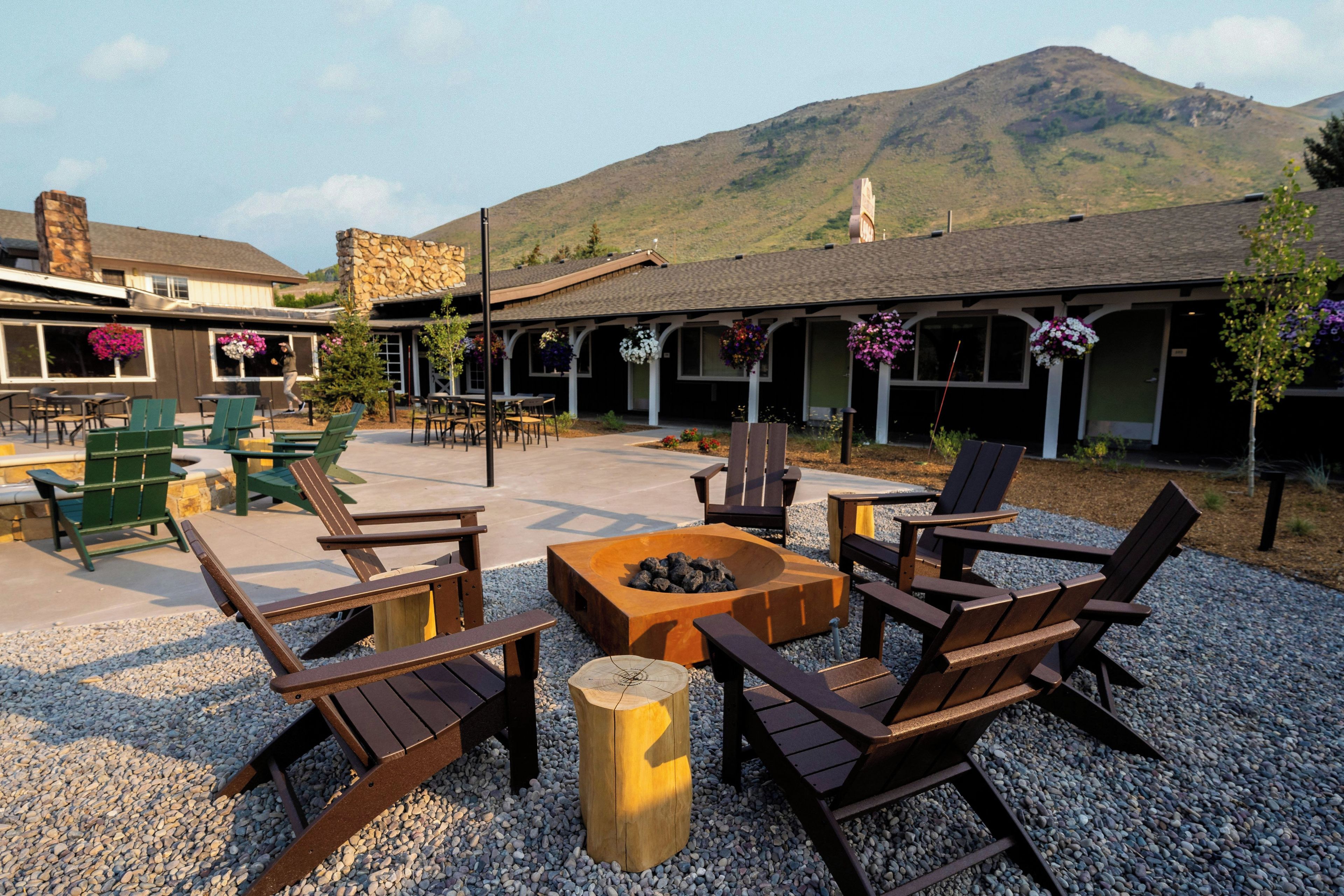 An outdoor seating area with wooden chairs and a fire pit, surrounded by gravel.