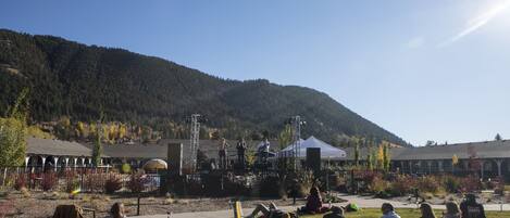 An outdoor event with a stage and audience in a park with a mountain backdrop.