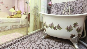 A bathroom with a bathtub, shower, and a bed with a teddy bear. - Love in Pearl Hostel (Dongshan)