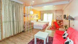 A room with a bed, a red sofa, a white table, and a large window. - Love in Pearl Hostel (Dongshan)