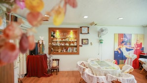 A dining area with a round table, chairs, and a bookshelf with various items. - Love in Pearl Hostel (Dongshan)