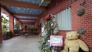 A brick building with a large teddy bear, potted plants, and a sign with text. - Love in Pearl Hostel (Dongshan)