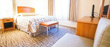 Ein Hotelzimmer mit Bett, einer Sitzbank, einem Schreibtisch und einem Sessel.