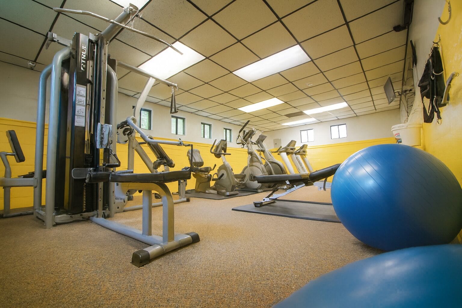 A gym with various exercise equipment, including a leg press machine and stationary bikes.