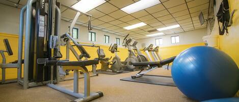 A gym with various exercise equipment, including a leg press machine and stationary bikes.