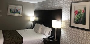 A hotel room with a bed, two bedside lamps, a nightstand with a phone, and framed artwork on the walls.