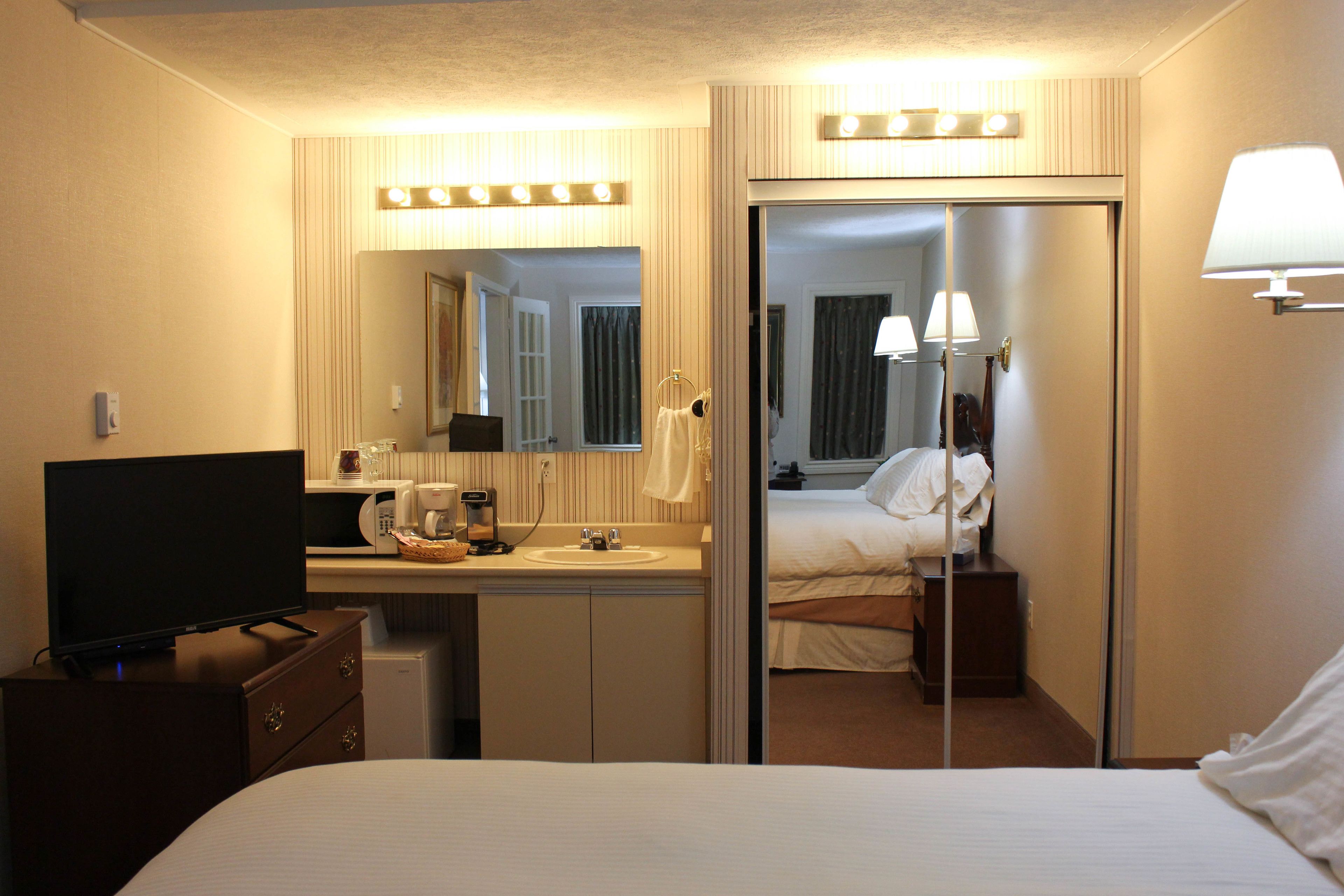 Une chambre d’hôtel équipée d’un lit, d’une télévision, d’un lavabo, d’un miroir et d’une armoire.