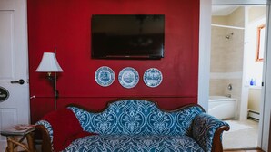 A room with a red wall, a wooden sofa, a flat-screen TV, and three blue and white patterned plates. - The Chepstow Inn (Brockton)