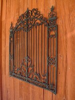 Una reja de hierro forjado con diseños intrincados, fijada a un muro de madera.