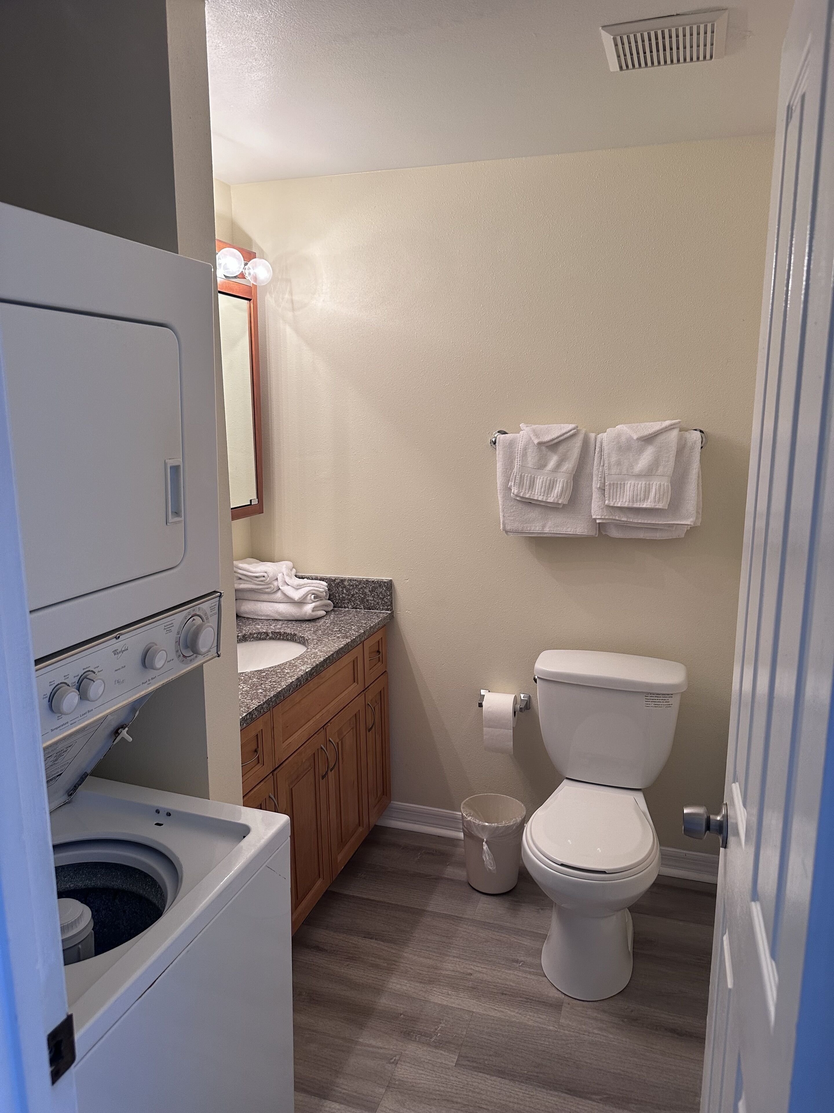Une petite salle de bain équipée d’un lave-linge, d’un lavabo et de toilettes.