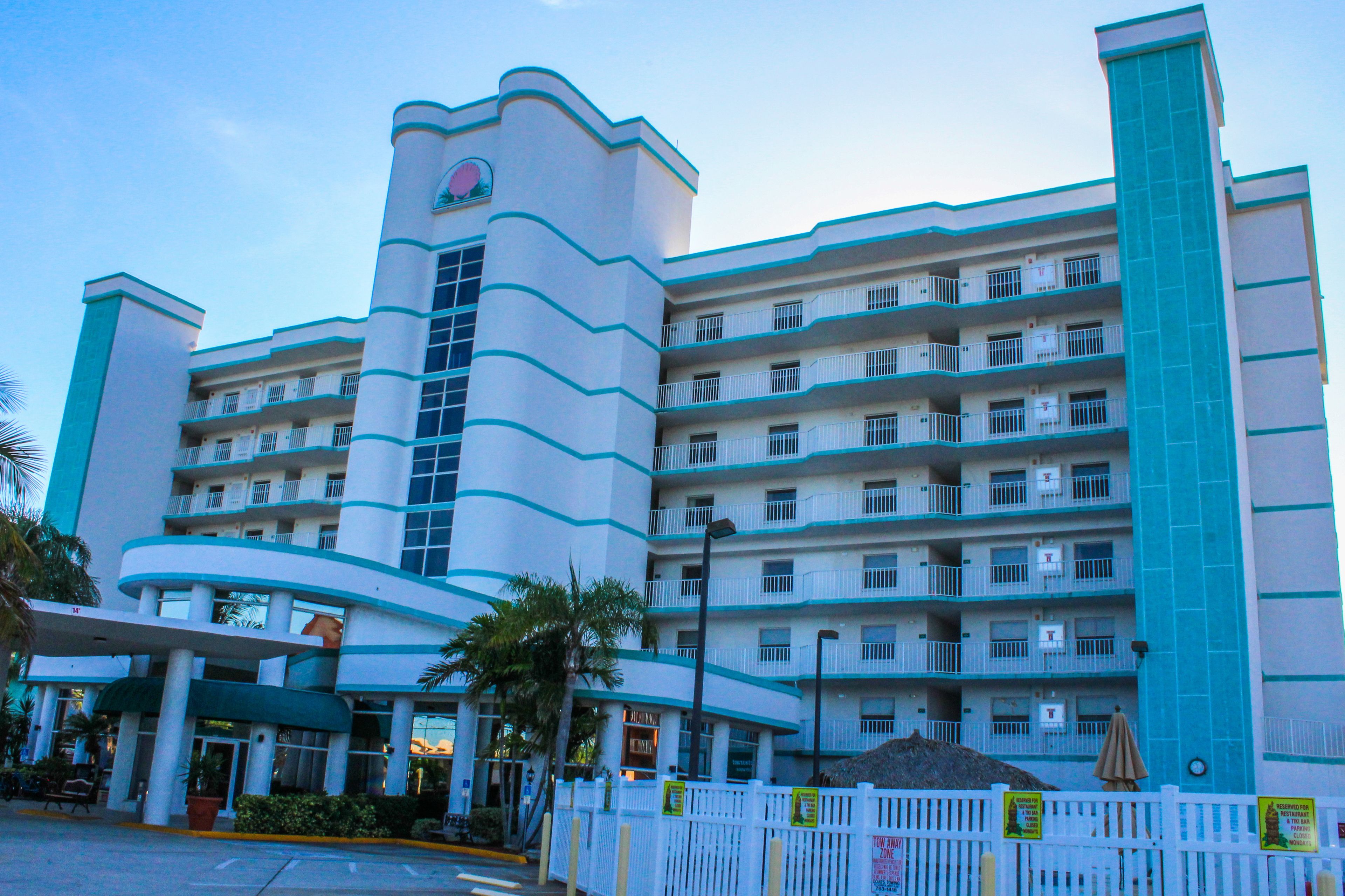 Um hotel de vários andares com fachada curva marcante, varandas em cada pavimento e entrada central coberta.
