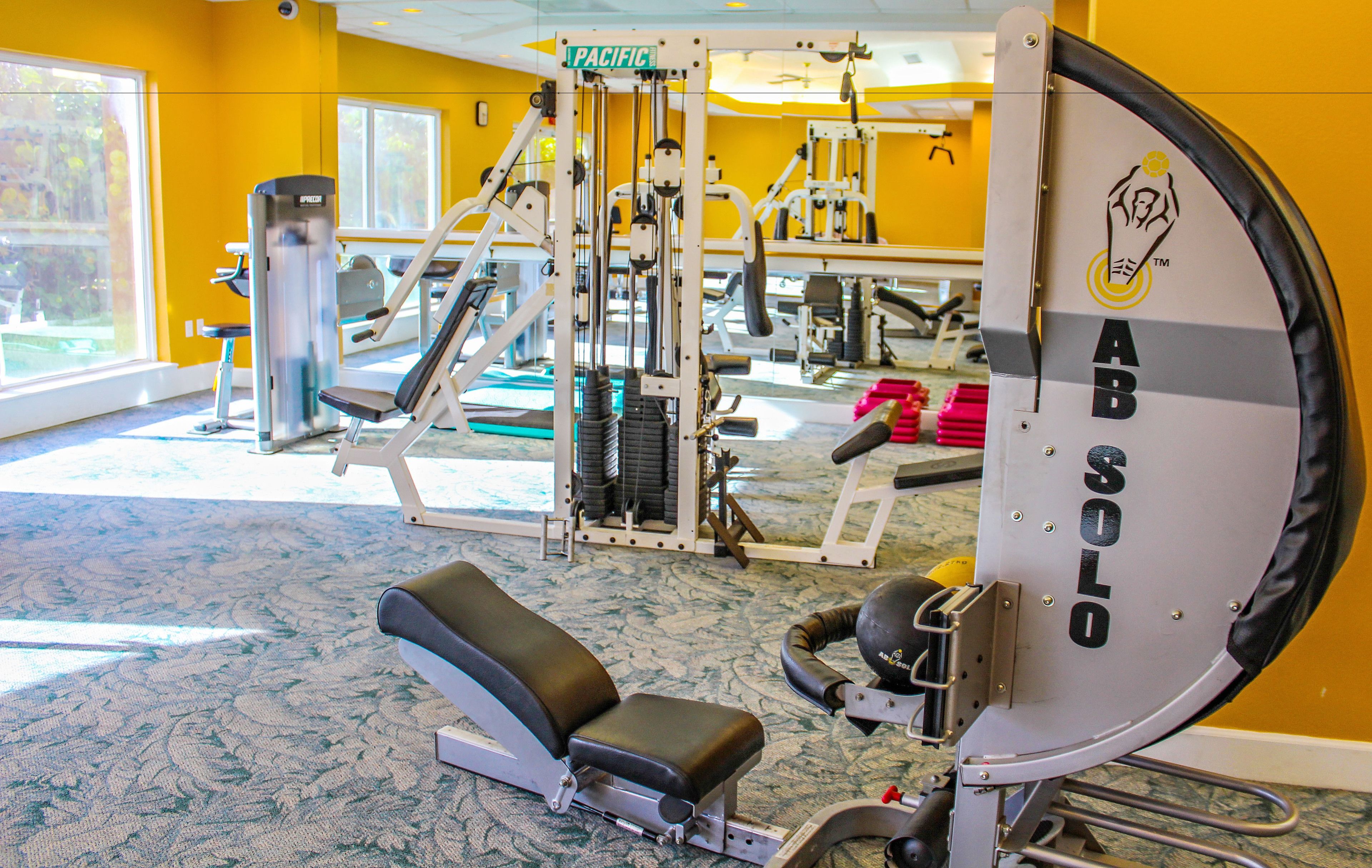 A gym with exercise equipment, a weight bench, and a large mirror.