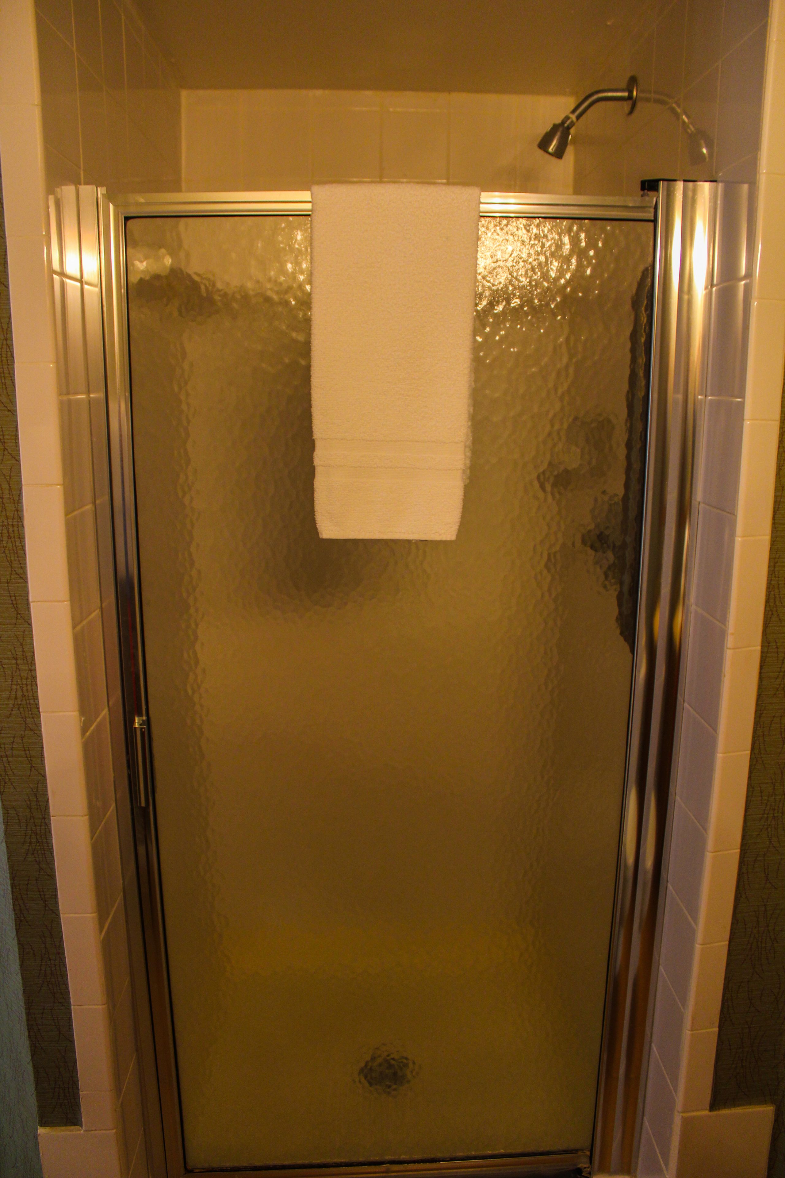 A glass-enclosed shower stall with a white towel hanging on the door.