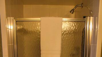 A glass-enclosed shower stall with a white towel hanging on the door.
