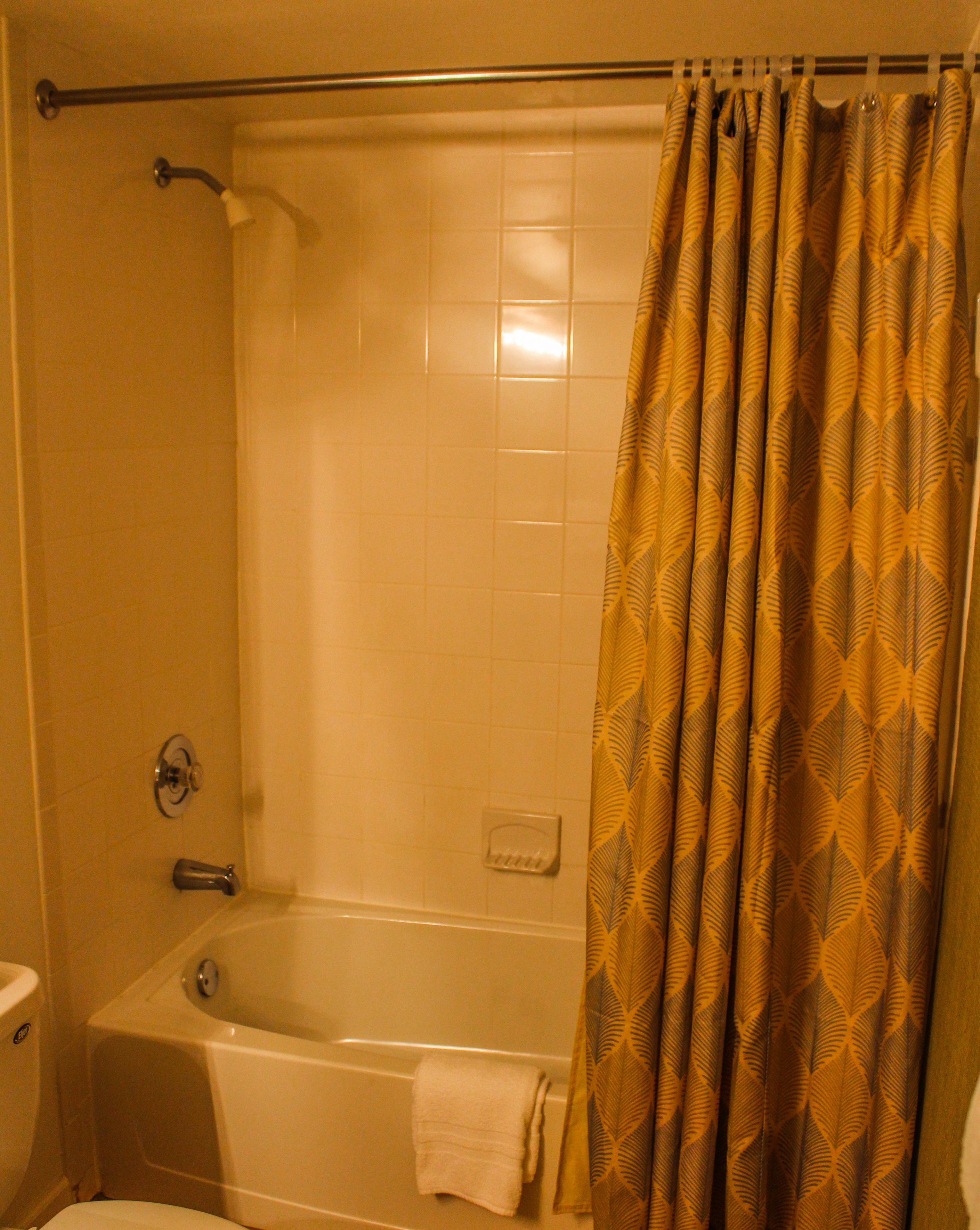 Een badkamer met een bad, toilet en een douchegordijn.
