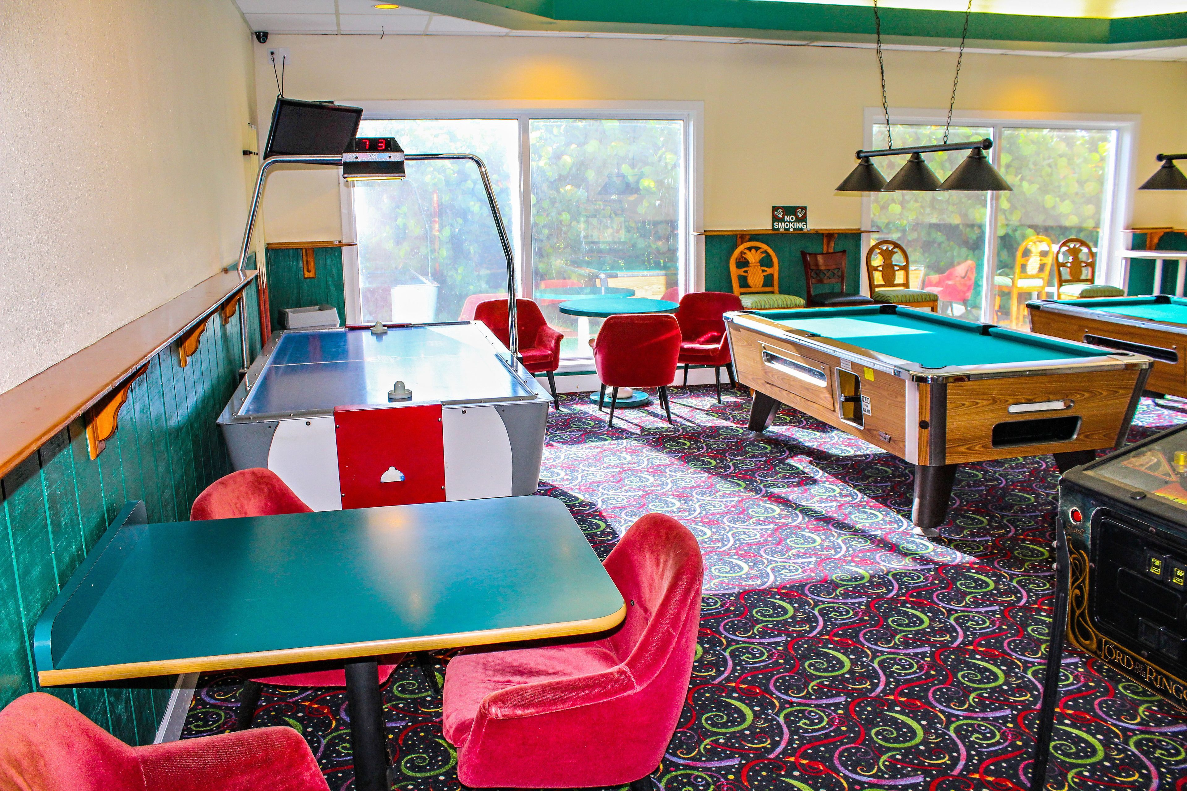 A pool table area with a pool table, red chairs, and a colorful patterned carpet.