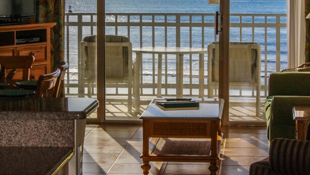 Una habitación con cocina, una mesa de comedor, un sofá y vistas al océano a través de una puerta corrediza de vidrio.