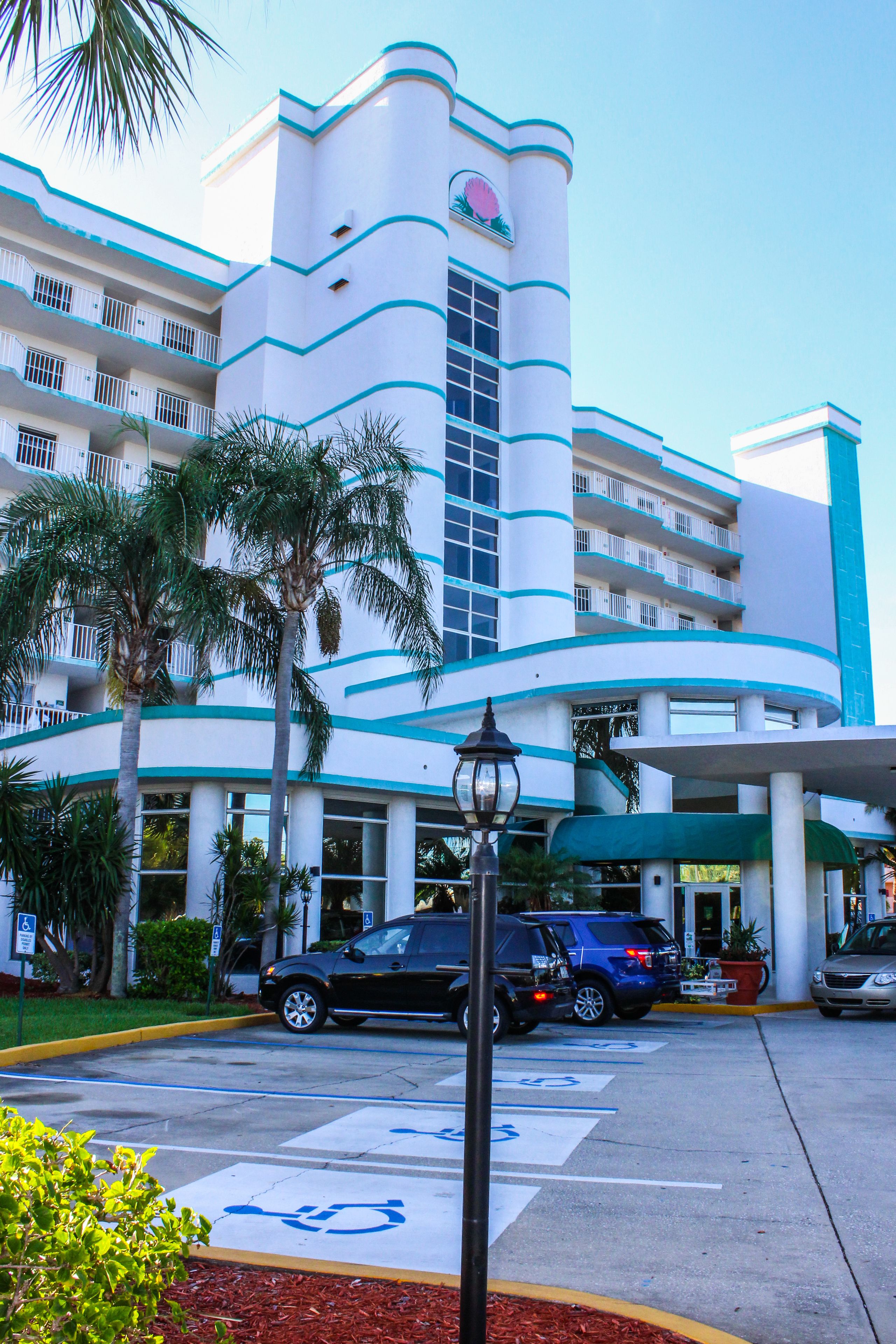 Un hotel con fachada curva, varios balcones y una palmera en primer plano.
