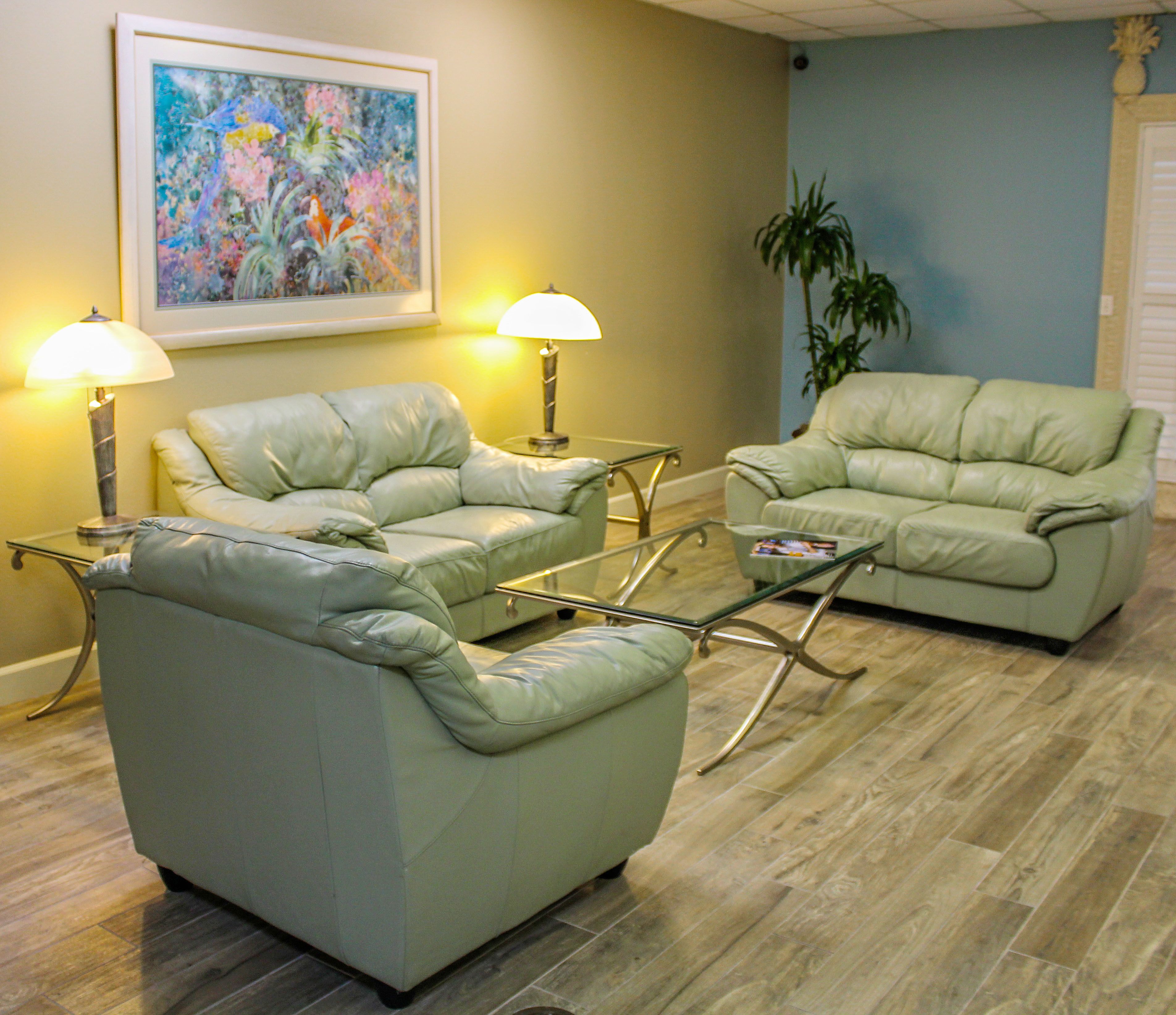 A living room with two leather sofas, a glass coffee table, and two floor lamps.