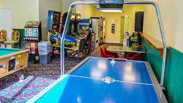 A room with a pool table, arcade games, and a dartboard.