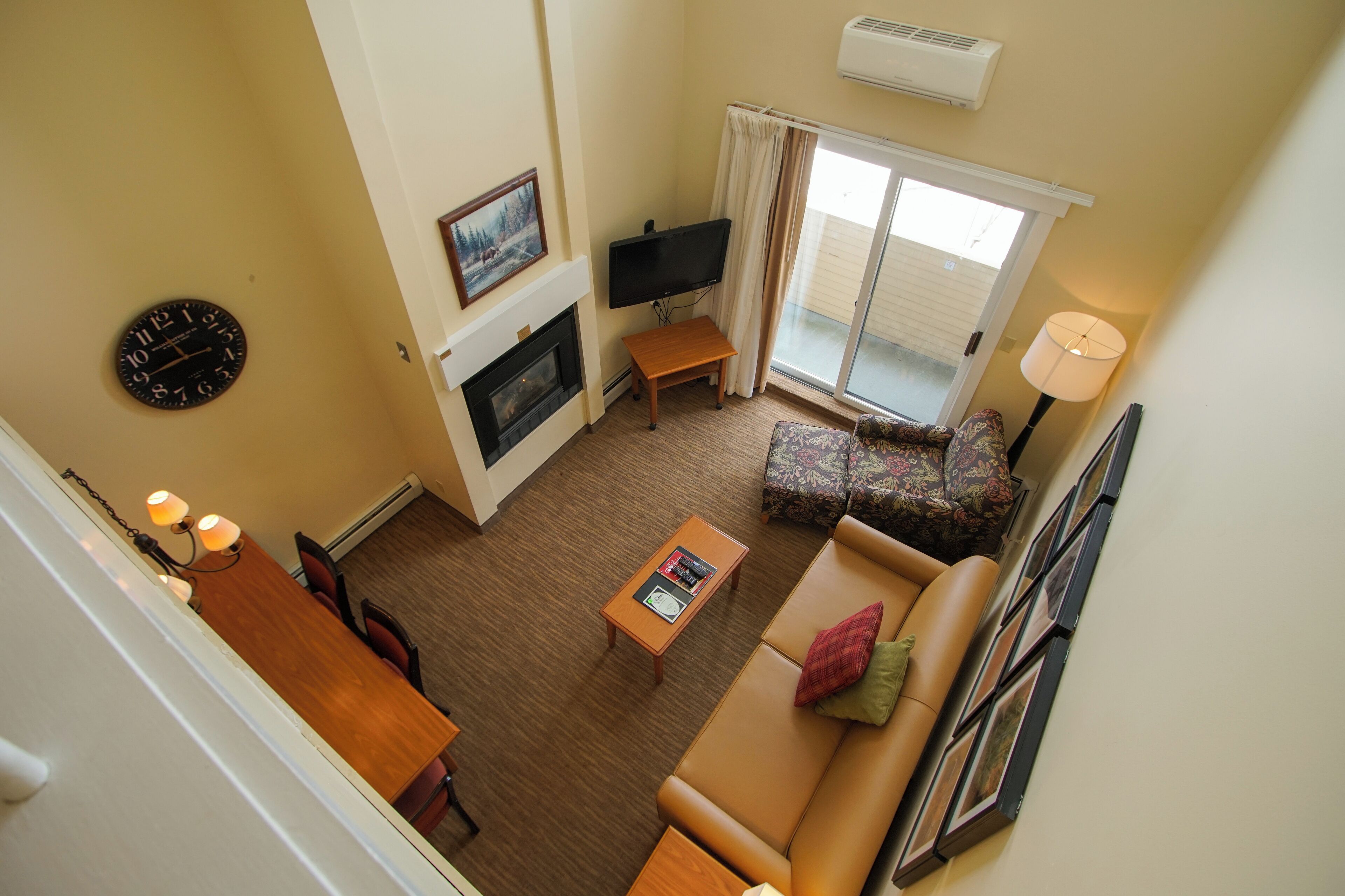 A living room with a fireplace, a television, a sofa, a coffee table, and a dining area with chairs.