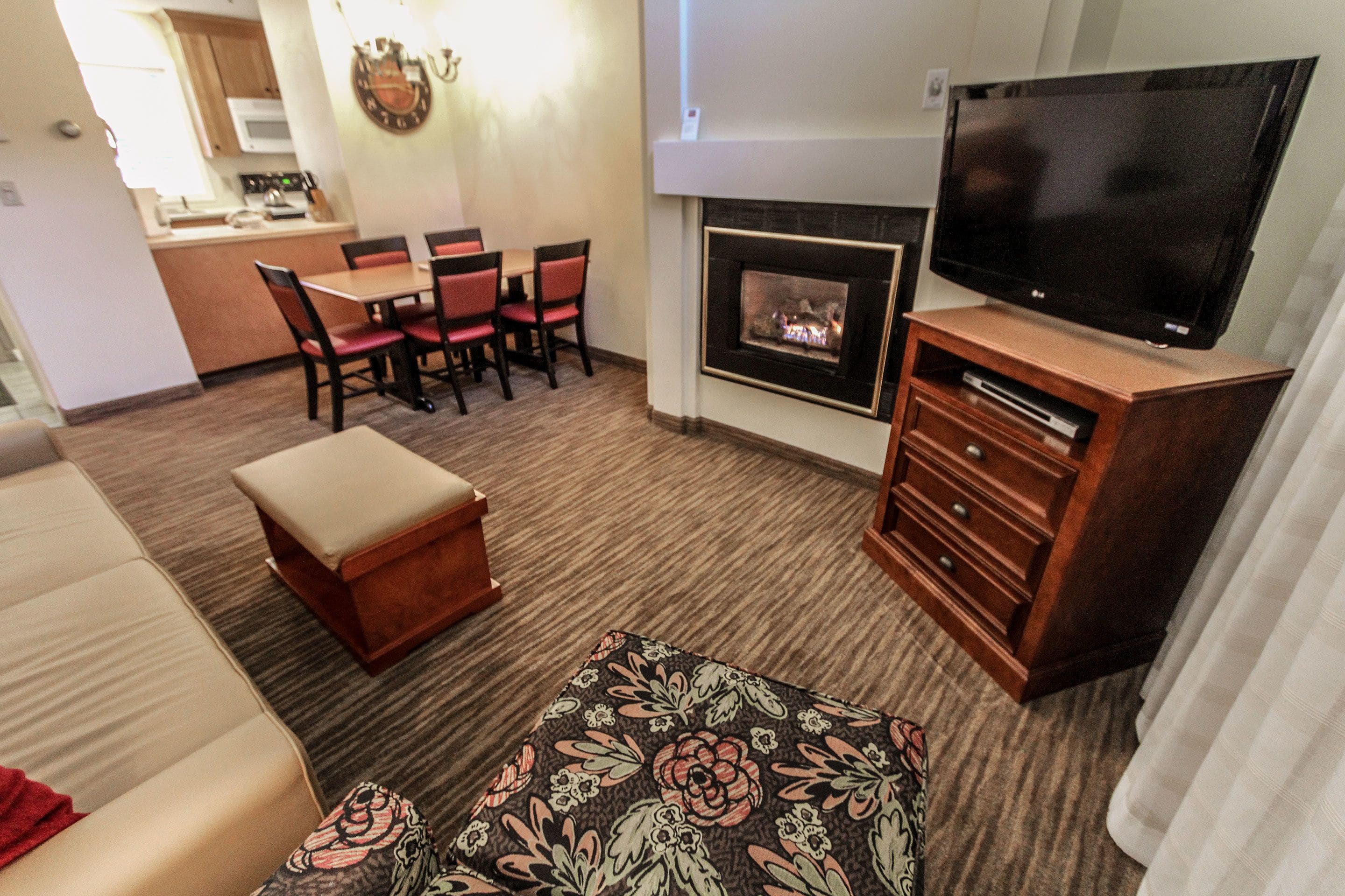Una sala de estar con televisión de pantalla plana, chimenea, comedor con sillas y sofá.