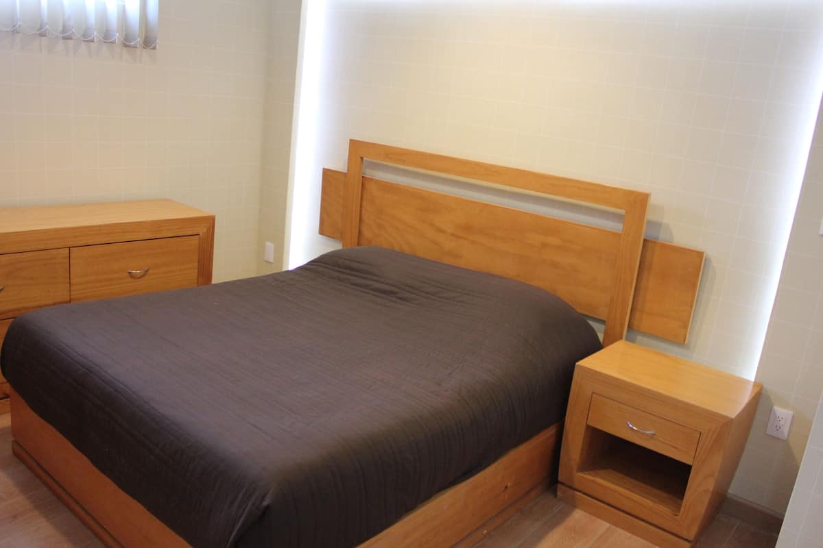 Une chambre à coucher avec un lit en bois, une table de chevet et une commode en bois.