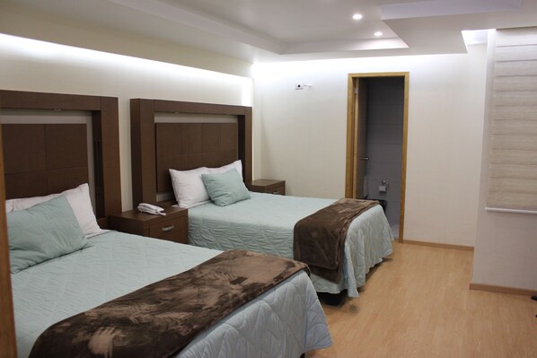 Une chambre d’hôtel avec deux lits, des têtes de lit en bois et un plancher en bois.