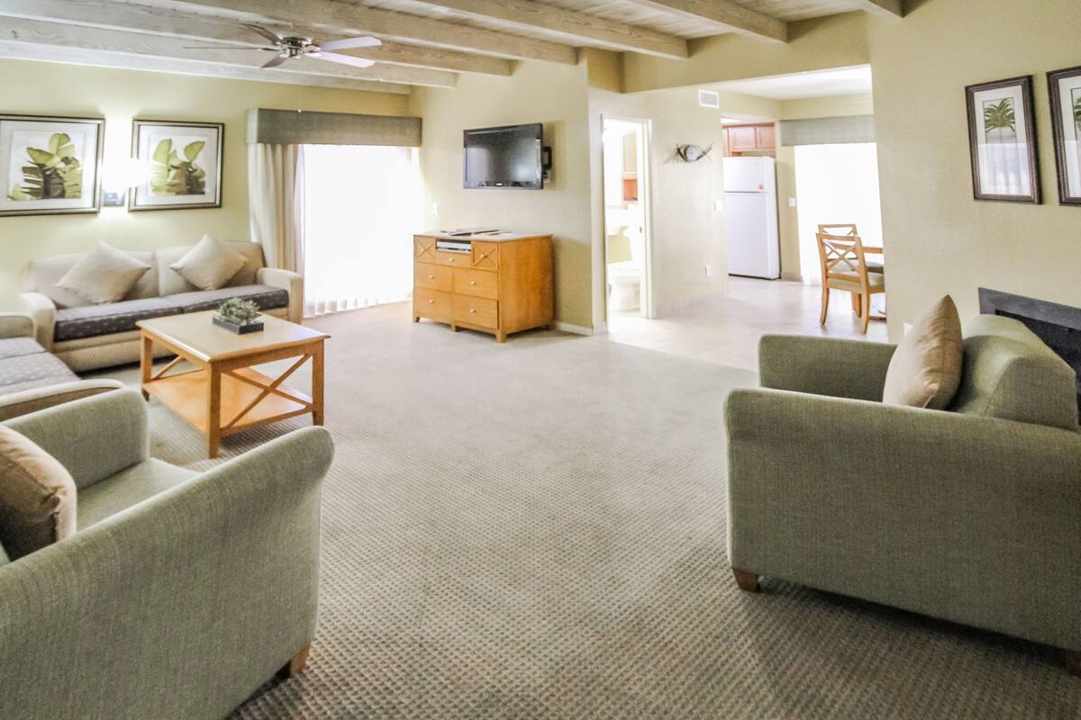 A spacious living area with a sofa, a coffee table, and a TV mounted on the wall.
